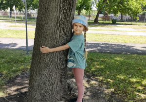 Dziewczynka przytula się do drzewa